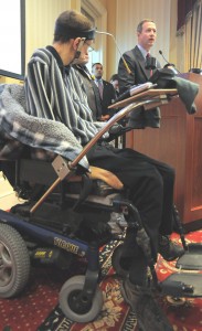 Man in wheelchair pecks out words on computer to communicate.