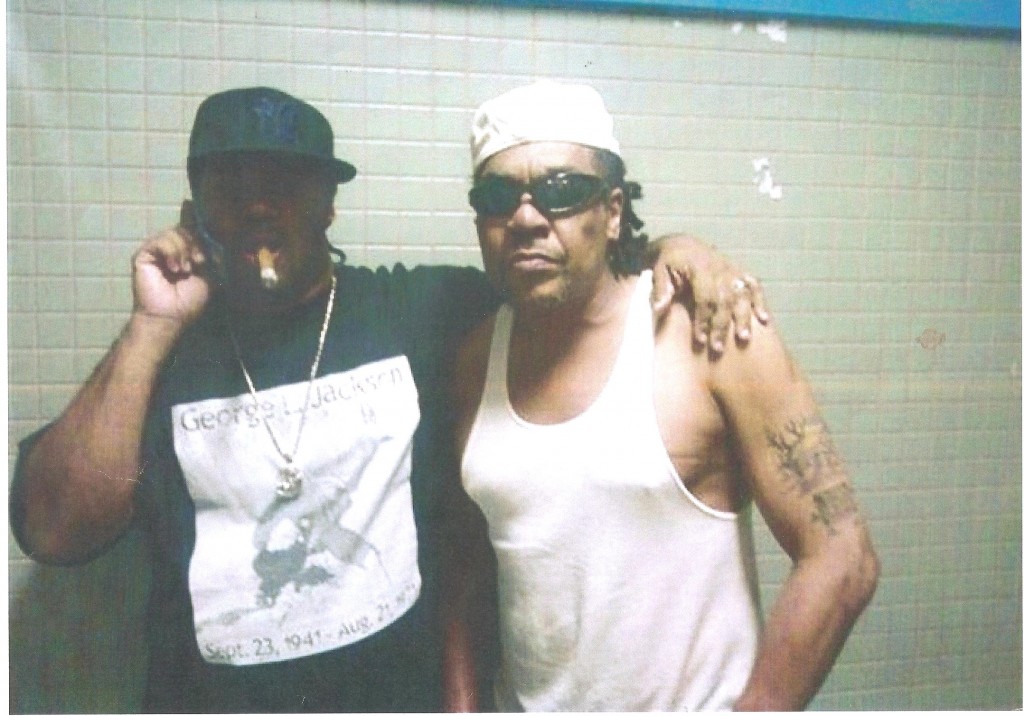 According a Republican delegate who released this photo, Black Guerrilla Family Founder Ray Alevas talks on a cell phone with his arm around top Maryland BGF Member Eric Brown. The photo was reportedly taken in prison on a cell phone camera by another inmate. 