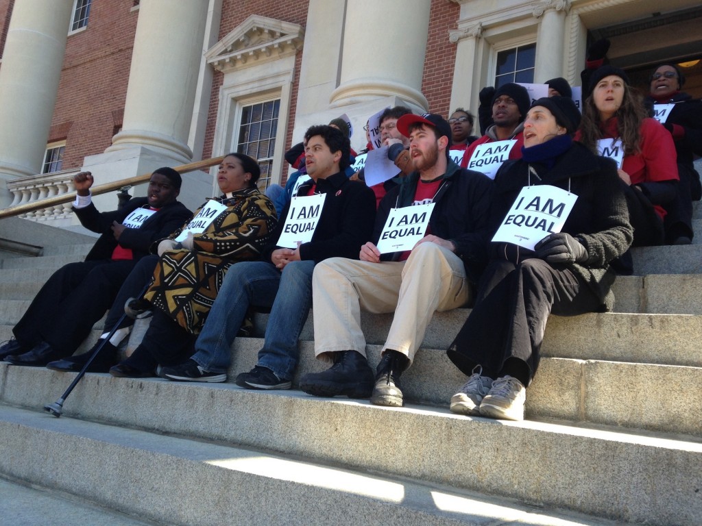 Fifteen Unite Here protesters stage sit-down on State House steps.