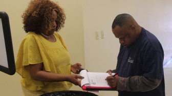 Carla Walker, the time trial administrator at Melwood, watches Brian Beckham as he signs a form stating that the mock time trial, conducted to demonstrate what the process used to entail, was administered fairly. Capital News Service photo by Josh Magness.