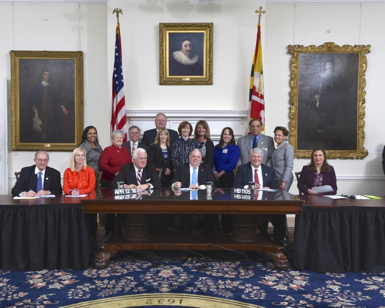 Gov. Hogan signs bill to investigate Howard County school board release of information. Behind him are legislators of both parties and school board candidates. 