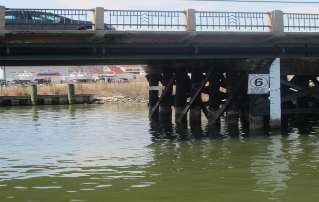 Measuring rods mark water levels under a bridge in Chesapeake Beach.  In low-lying coastal areas, high tides sometimes prevent charter boats from clearing bridges and flood roadside ditches. Capital News Service photo by Sydney Paul