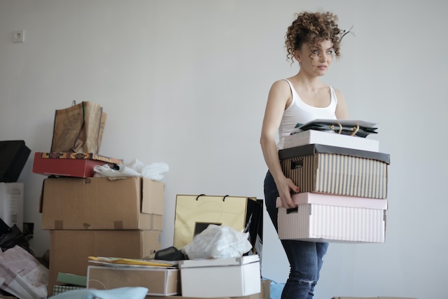 Woman carrying a pile of boxes while preparing for a long-distance move