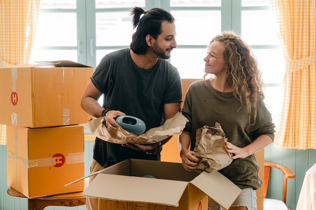 Happy couple unpacking cardboard boxes after their long-distance move